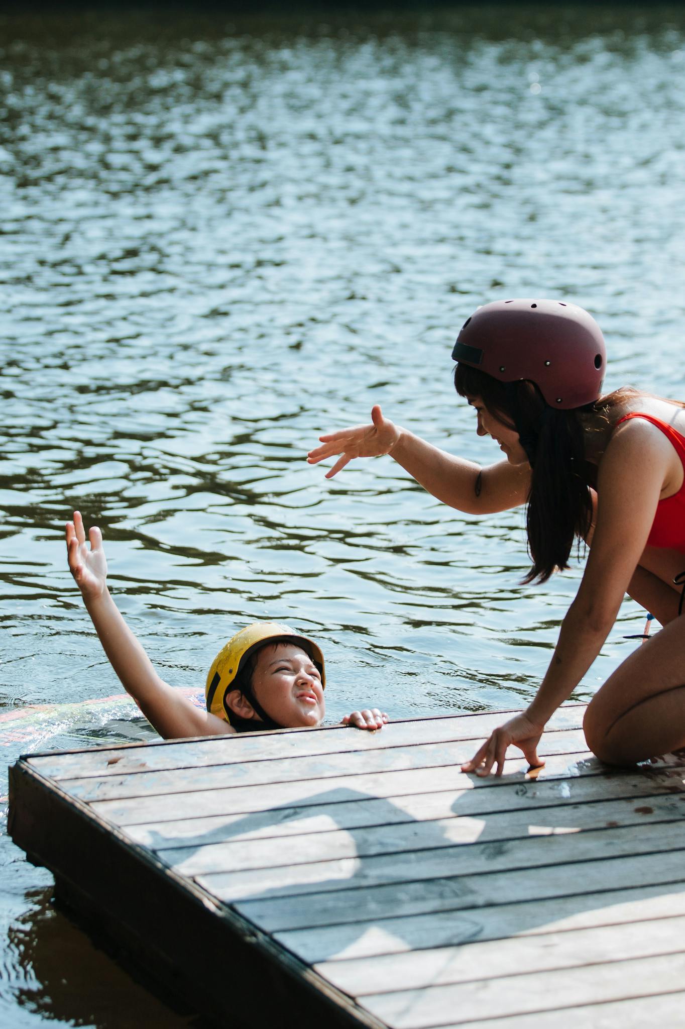 Woman helping her child in a lake, promoting outdoor active lifestyle and swimming safety.